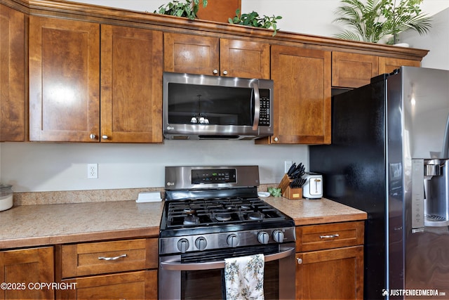 kitchen featuring light countertops, appliances with stainless steel finishes, and brown cabinetry