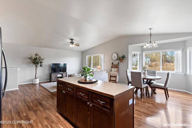 kitchen with light countertops, ceiling fan with notable chandelier, decorative light fixtures, wood finished floors, and lofted ceiling