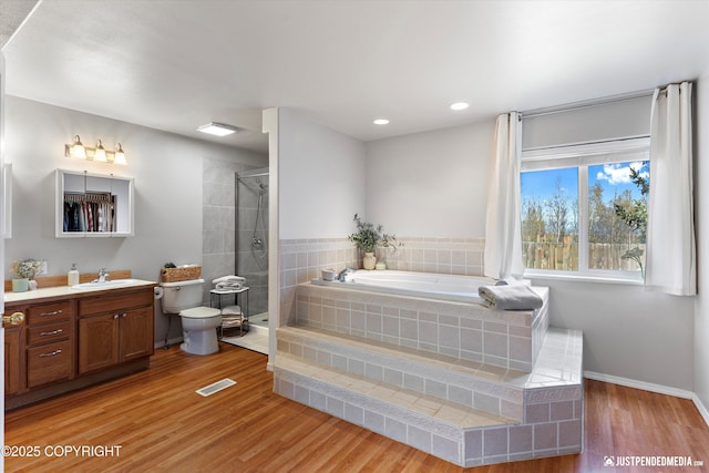 full bathroom with vanity, a garden tub, wood finished floors, baseboards, and a stall shower