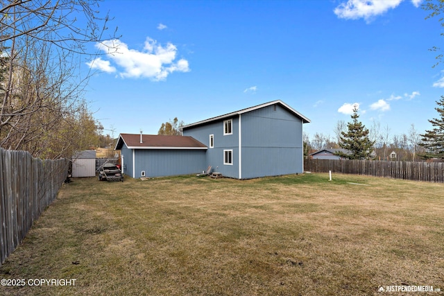back of property with a fenced backyard, an outbuilding, and a lawn