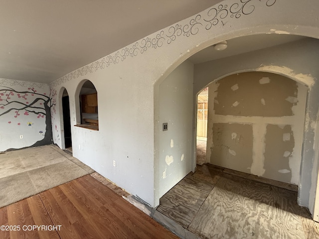 hall featuring wood finished floors and arched walkways
