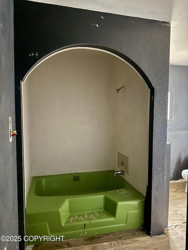 bathroom with a bath and wood finished floors