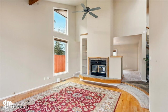 12100 Woodway Cir, Anchorage, AK 99516 - living area with a high ceiling, wood finished floors, ceiling fan, a glass covered fireplace, and baseboards