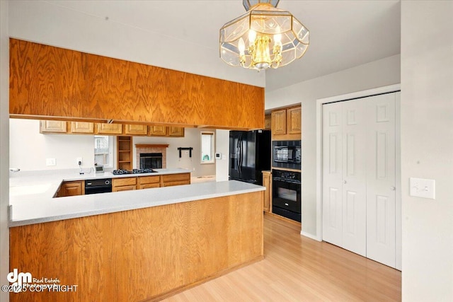 12100 Woodway Cir, Anchorage, AK 99516 - kitchen with black appliances, light wood finished floors, light countertops, a chandelier, and a peninsula
