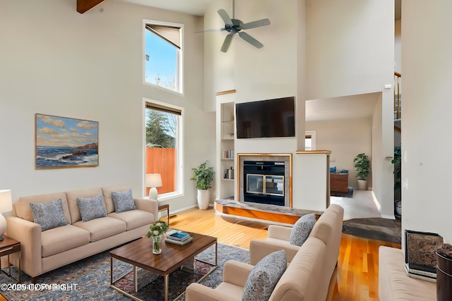 12100 Woodway Cir, Anchorage, AK 99516 - living room featuring a towering ceiling, a fireplace, wood finished floors, a ceiling fan, and baseboards