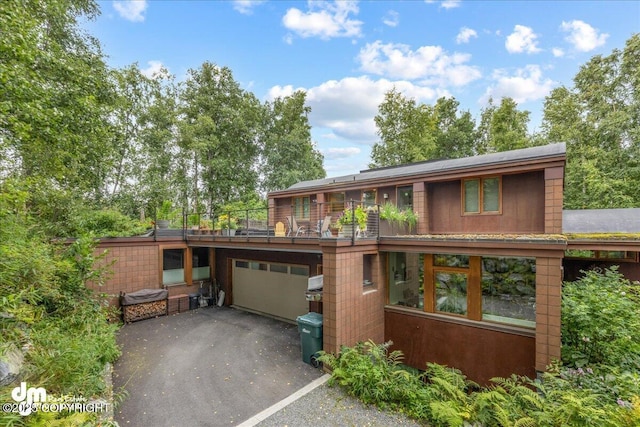 prairie-style house with an attached garage, a balcony, and driveway