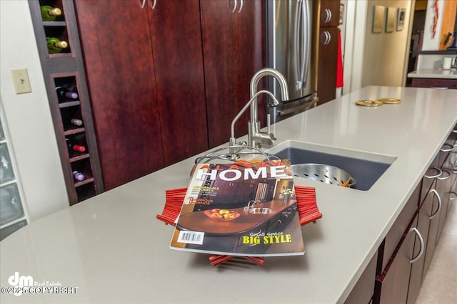 kitchen featuring reddish brown cabinets, light countertops, and a sink