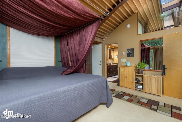 carpeted bedroom featuring ensuite bath and lofted ceiling