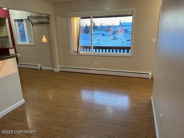 unfurnished room featuring baseboard heating, plenty of natural light, and baseboards