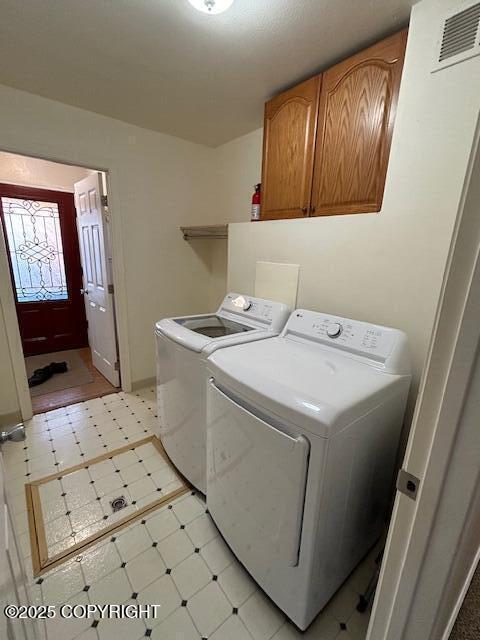 laundry area with independent washer and dryer, light floors, and cabinet space