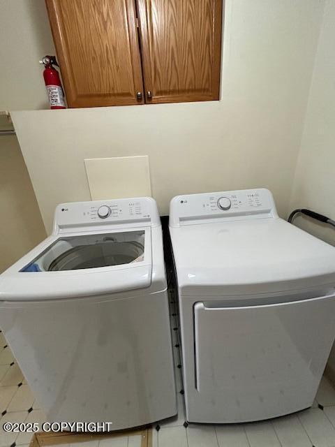 clothes washing area featuring cabinet space, washer and clothes dryer, and light tile patterned floors