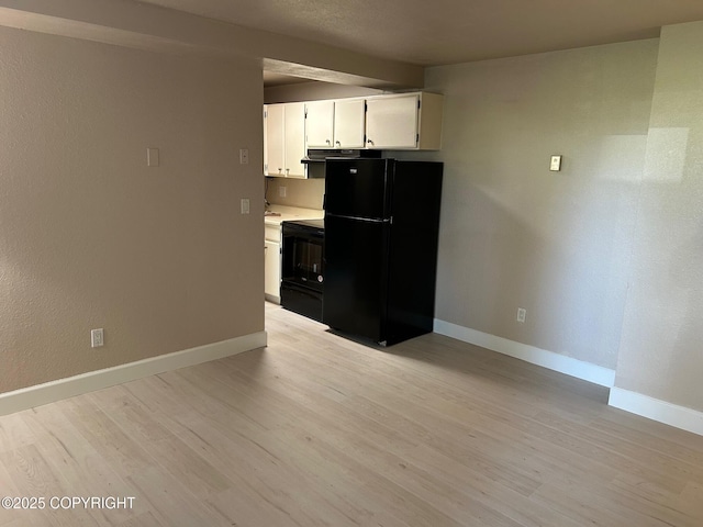 kitchen with black appliances, baseboards, light wood-style floors, and white cabinetry