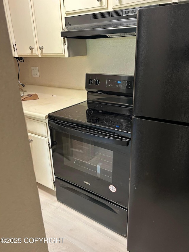 kitchen featuring black appliances, under cabinet range hood, light countertops, and white cabinetry