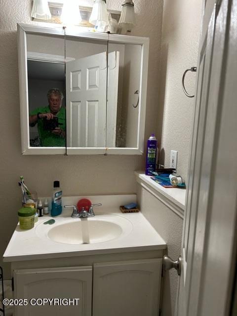 bathroom with a textured wall and vanity