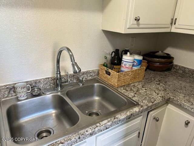 kitchen view of a sink, white cabinetry, and light countertops
