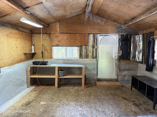 interior space featuring lofted ceiling and wood walls
