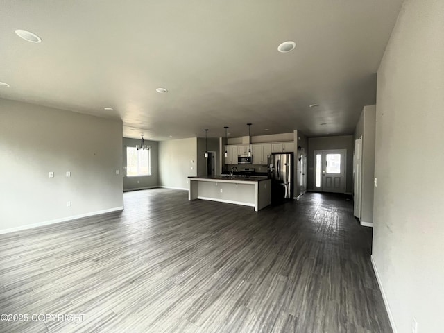 49045 Gemini Ct, Soldotna, AK 99669 - unfurnished living room featuring a sink, baseboards, dark wood finished floors, and a chandelier
