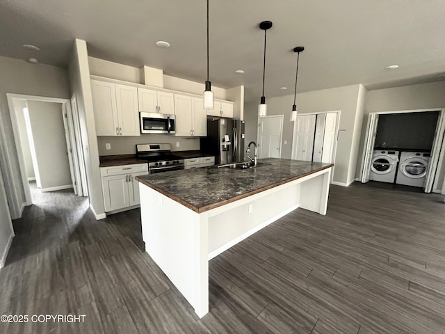 49045 Gemini Ct, Soldotna, AK 99669 - kitchen with washing machine and clothes dryer, dark countertops, a sink, white cabinets, and stainless steel appliances