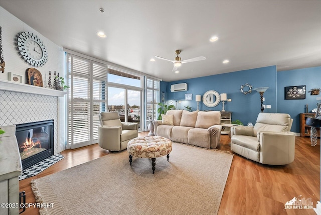 222 E 7th Ave # 106, Anchorage, AK 99501 - living area featuring a tiled fireplace, a ceiling fan, recessed lighting, a wall unit AC, and wood finished floors