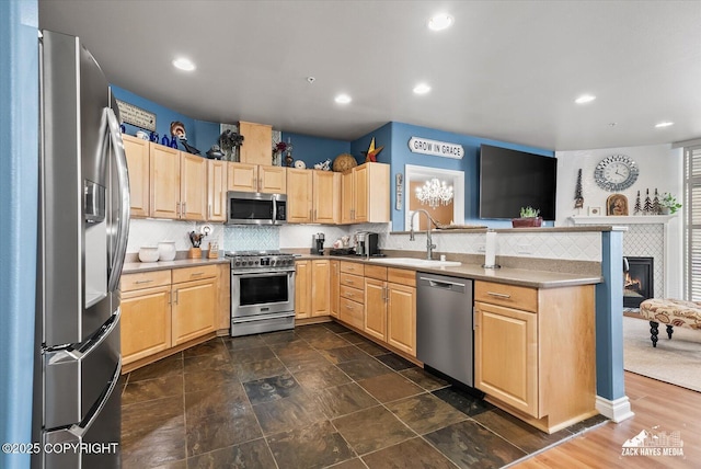 222 E 7th Ave # 106, Anchorage, AK 99501 - kitchen featuring a peninsula, light brown cabinetry, tasteful backsplash, a sink, and stainless steel appliances