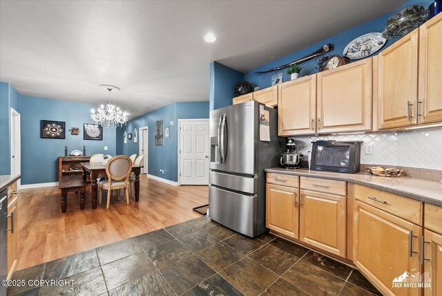 222 E 7th Ave # 106, Anchorage, AK 99501 - kitchen with decorative backsplash, light brown cabinetry, a chandelier, and stainless steel fridge