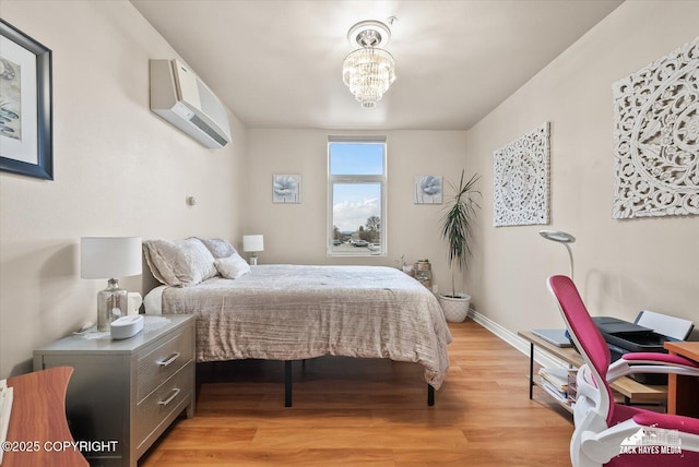 222 E 7th Ave # 106, Anchorage, AK 99501 - bedroom with an inviting chandelier, baseboards, light wood finished floors, and a wall unit AC