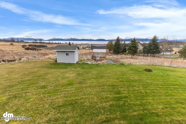 view of yard with an outdoor structure, a mountain view, and a storage unit