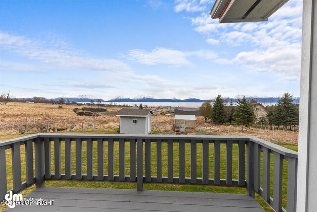 wooden terrace with a storage shed, a yard, an outdoor structure, and a mountain view