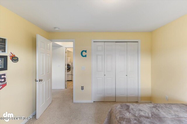 unfurnished bedroom with washer / dryer, carpet floors, baseboards, and a closet