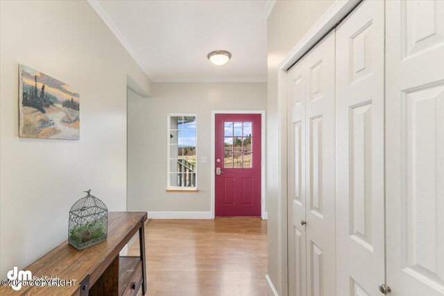 doorway with crown molding, baseboards, and wood finished floors