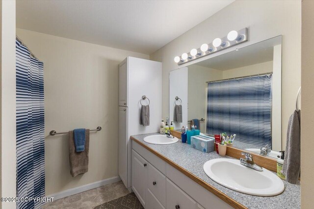 full bathroom with a sink, baseboards, tile patterned flooring, and double vanity