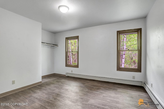 5900 E Liberty Ct, Wasilla, AK 99654 - unfurnished room featuring baseboard heating, plenty of natural light, wood finished floors, and baseboards