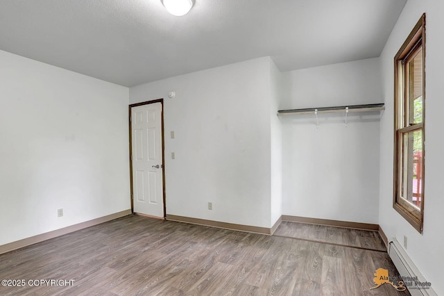 5900 E Liberty Ct, Wasilla, AK 99654 - unfurnished bedroom featuring a baseboard radiator, wood finished floors, and baseboards