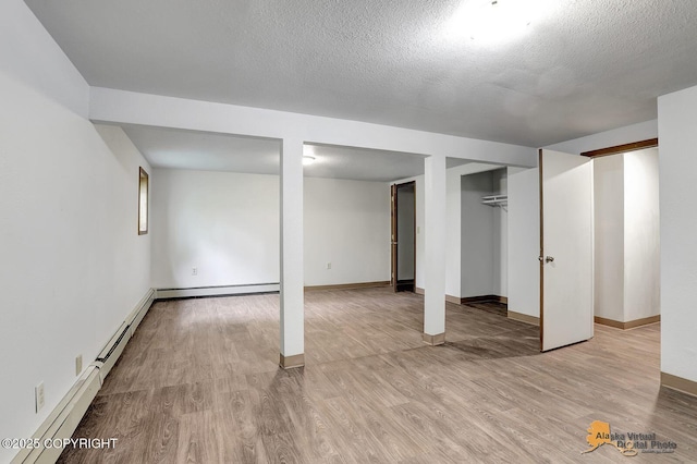 5900 E Liberty Ct, Wasilla, AK 99654 - finished basement featuring light wood-type flooring, baseboards, a textured ceiling, and a baseboard radiator