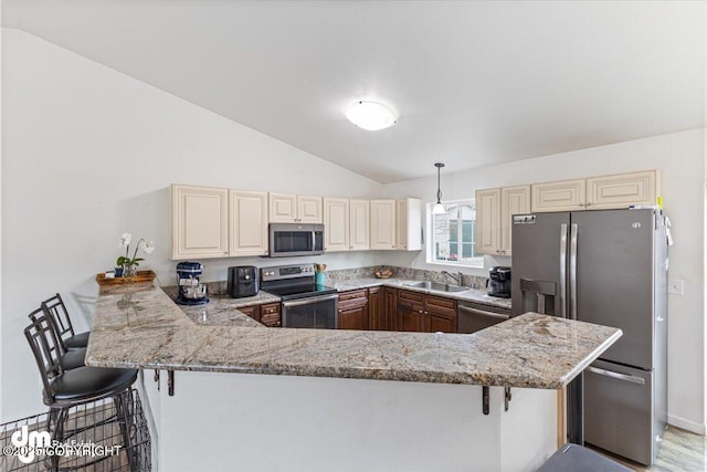 kitchen with a sink, a breakfast bar area, stainless steel appliances, a peninsula, and vaulted ceiling