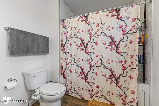 bathroom featuring a shower with shower curtain, toilet, and wood finished floors
