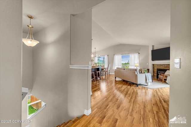 13050 Curry Ridge Cir, Eagle River, AK 99577 - living room featuring vaulted ceiling, light wood-type flooring, a tile fireplace, a chandelier, and baseboards