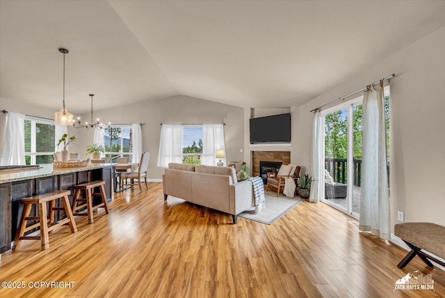 13050 Curry Ridge Cir, Eagle River, AK 99577 - living area with vaulted ceiling, healthy amount of natural light, light wood-style flooring, a tiled fireplace, and a chandelier