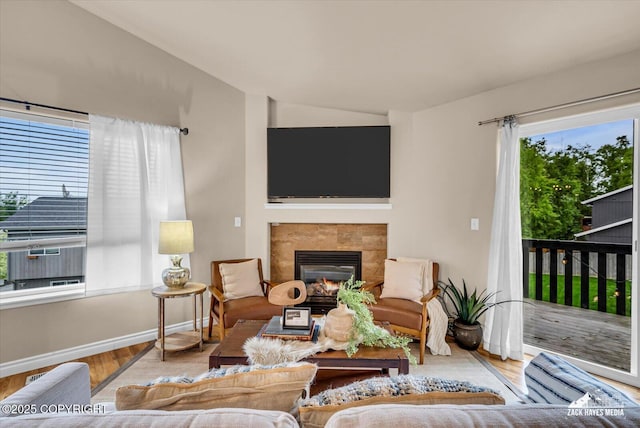 13050 Curry Ridge Cir, Eagle River, AK 99577 - living area featuring vaulted ceiling, a tile fireplace, wood finished floors, and baseboards