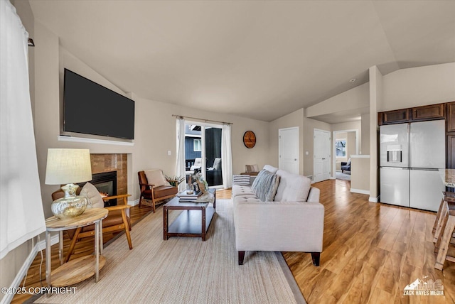 13050 Curry Ridge Cir, Eagle River, AK 99577 - living area featuring vaulted ceiling, light wood-style flooring, a fireplace, and baseboards