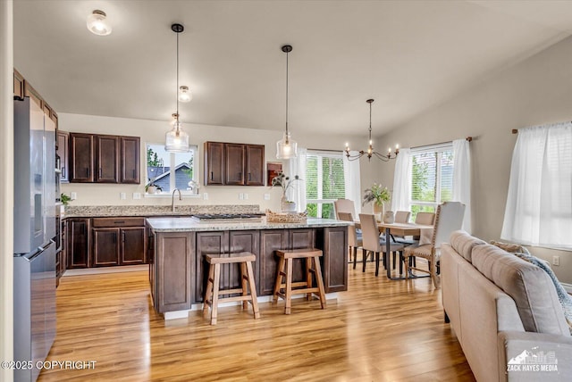 13050 Curry Ridge Cir, Eagle River, AK 99577 - kitchen featuring light wood finished floors, stainless steel appliances, a breakfast bar area, a chandelier, and dark brown cabinetry
