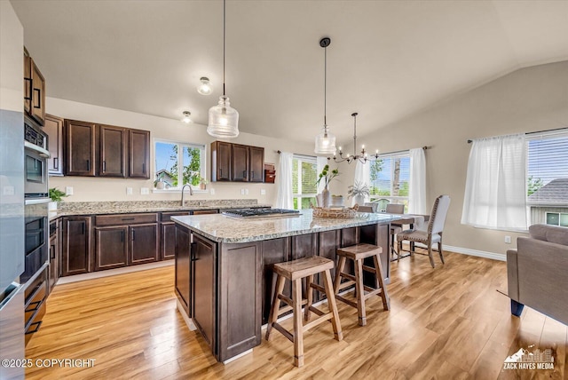 13050 Curry Ridge Cir, Eagle River, AK 99577 - kitchen featuring vaulted ceiling, a sink, light wood-style flooring, a breakfast bar area, and dark brown cabinets