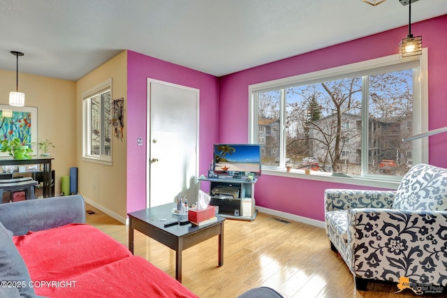 living room featuring baseboards, visible vents, and wood finished floors
