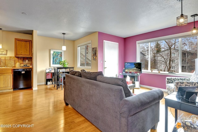 living area featuring a textured ceiling, baseboards, and light wood-style flooring