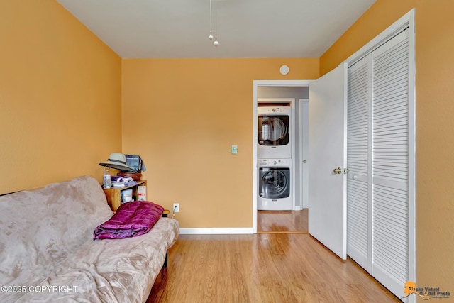 living area featuring wood finished floors, baseboards, and stacked washer / drying machine