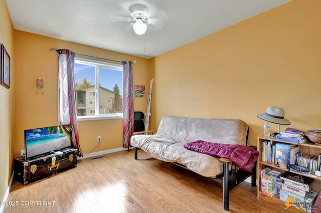 living area featuring baseboards, a ceiling fan, wood finished floors, and visible vents