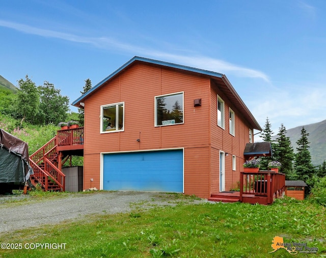 exterior space featuring a wooden deck, an attached garage, driveway, and stairway