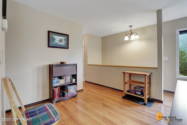 living area with an inviting chandelier, baseboards, and wood finished floors
