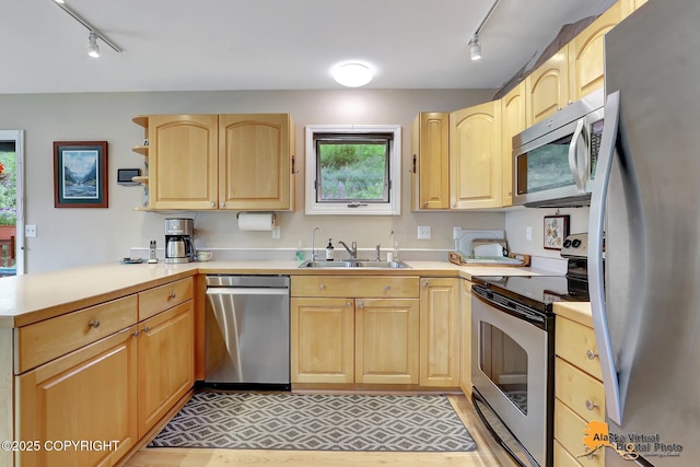 kitchen with track lighting, a peninsula, light brown cabinetry, a sink, and stainless steel appliances
