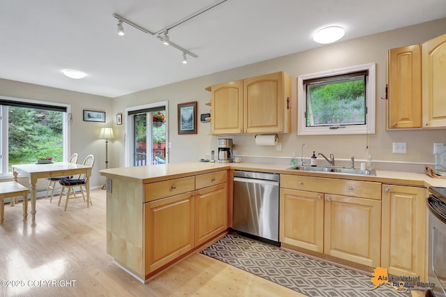 kitchen featuring a peninsula, light brown cabinets, light wood-style floors, a sink, and appliances with stainless steel finishes